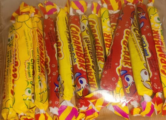 Bonbons colorés emballés, principalement jaunes et rouges, avec des motifs variés.