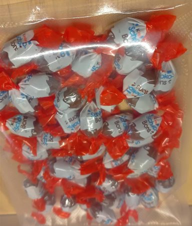 Bonbons enrobés de chocolat, emballés individuellement avec un papier rouge.